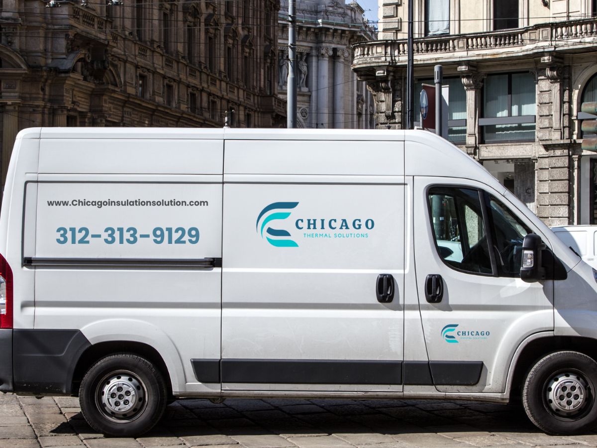 White van displaying a "Chicago" logo and contact info, parked on a city street near a building.