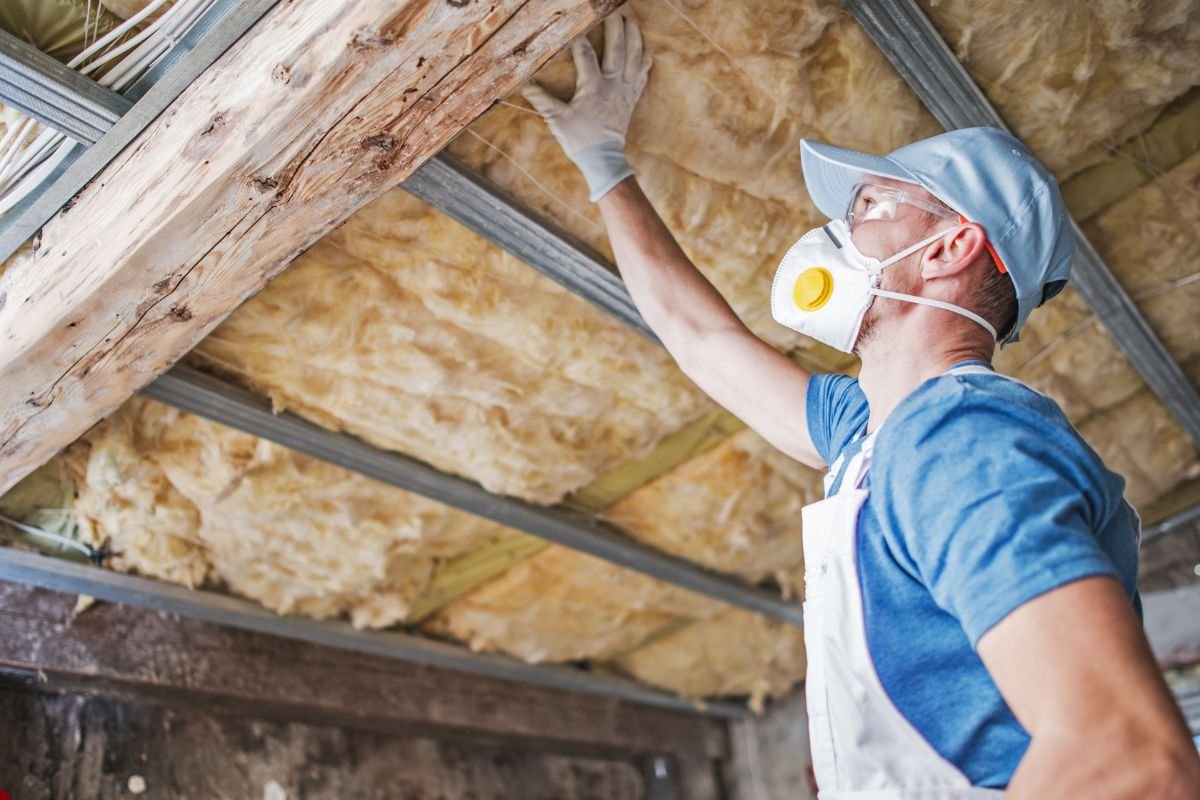 A man in a safety mask and gloves repairs a ceiling as part of a furniture repair service. 